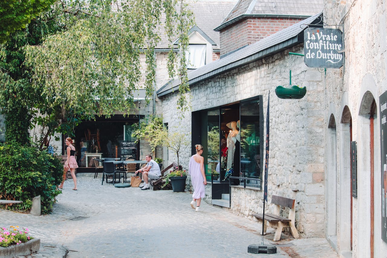 Picturesque Durbuy street with charming boutiques, greenery, and people enjoying a sunny day.